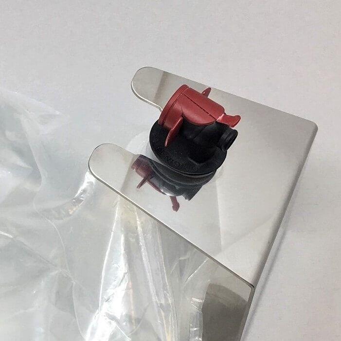 Rustfritt stål Bag-in-Box holder med rød og svart tappekran på en klar pose.