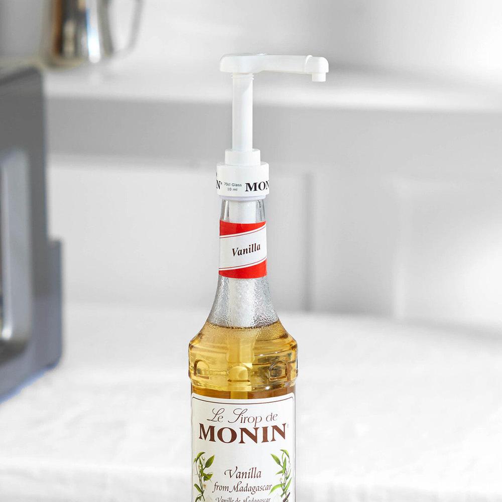 Hvit doseringspumpe på en Monin vaniljesirupflaske i glass, 70 cl.