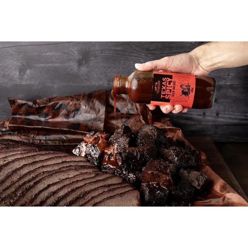 Traeger Texas Spicy BBQ-saus helles over skiver av grillet kjøtt.